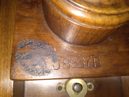 A maker's mark on the bottom of a tilt top tripod table.