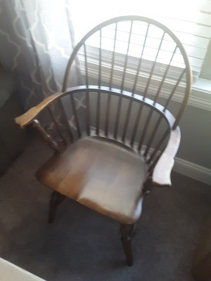A wooden chair with arms and spindles on the back.