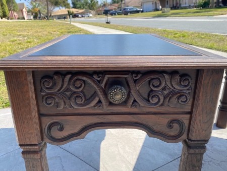 The ornate side to a leather topped table.