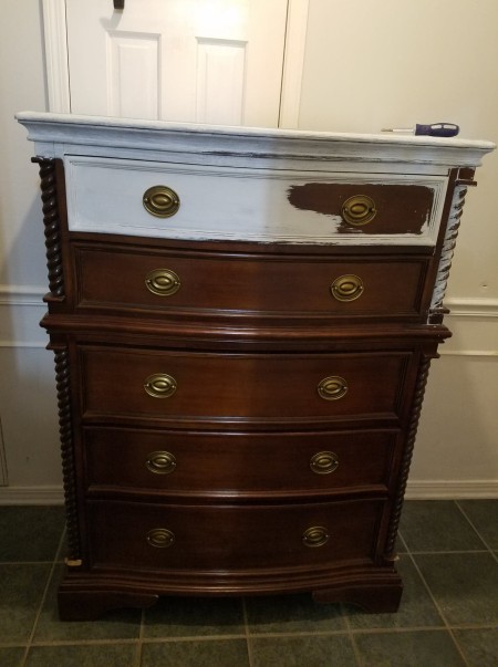A chest of drawers with the top drawer painted partly white.