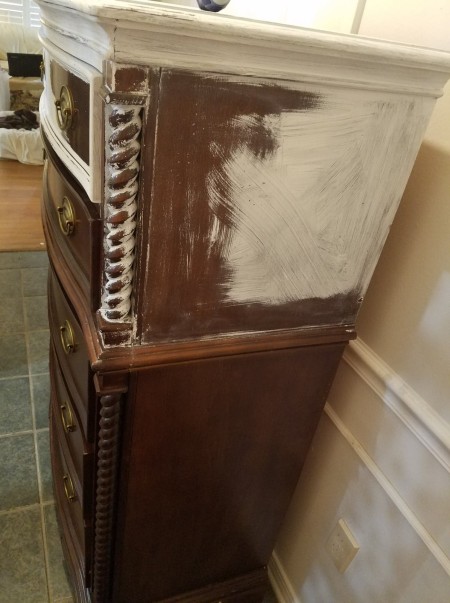 The side of the dresser with white paint at the top and back.