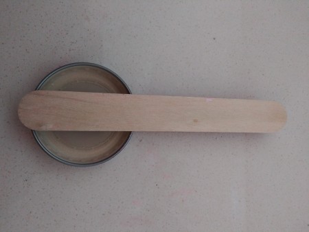 Gluing the craft stick to the bottlecap.