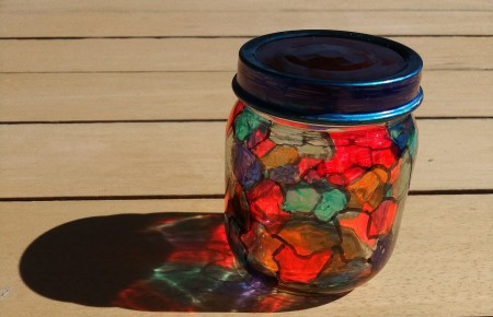 A recycled glass jar that has been decorated to resemble stained glass.
