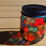 A recycled glass jar that has been decorated to resemble stained glass.