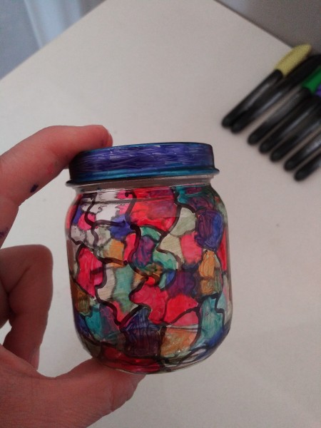 A recycled glass jar that has been decorated to resemble stained glass.