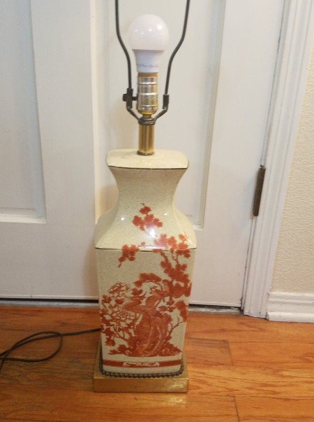A cream colored lamp with red decorations.
