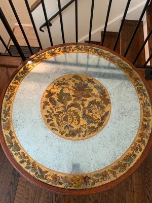 A round coffee table with an ornate top.