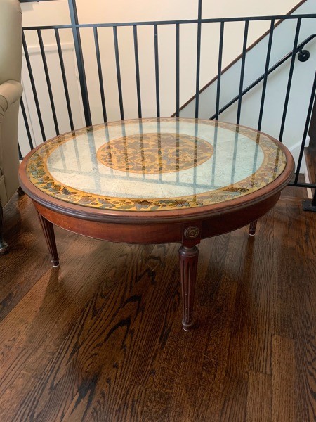 A round coffee table with an ornate top.