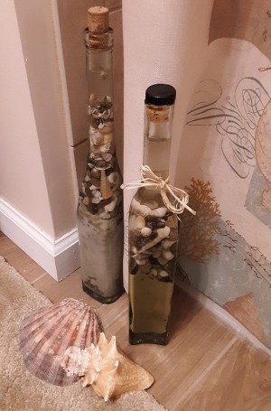 A decorative bottle filled with sand and shells.