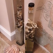 A decorative bottle filled with sand and shells.