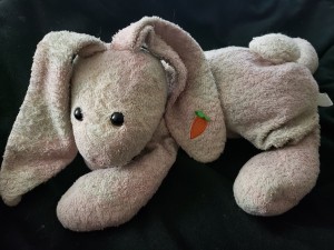 A stuffed rabbit with a carrot on its ear.