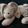 A stuffed rabbit with a carrot on its ear.