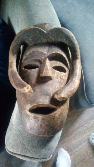A carved wooden mask in a primitive style.