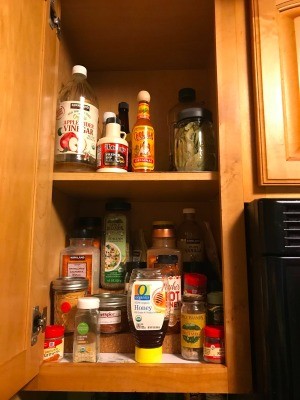 A cabinet containing spices and other cooking ingredients.