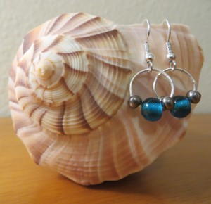 Two bead and wire earrings hanging on a seashell.