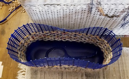 A plastic basket that is broken at the top, with crochet below.