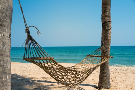 A hammock on a sandy beach.