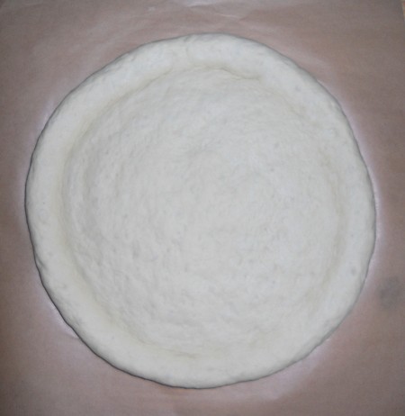 The pizza dough stretched into a circle.