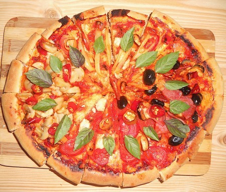 The baked pizza with 4 quadrants of toppings, cut into slices.