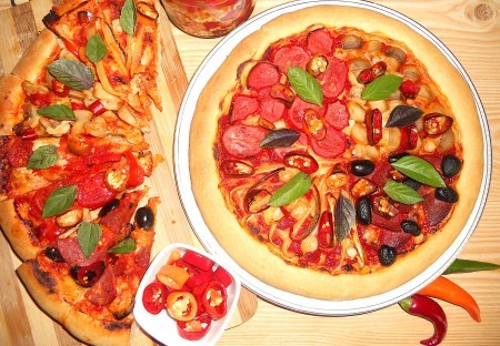 A baked pizza next to slices of pizza.
