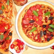 A baked pizza next to slices of pizza.