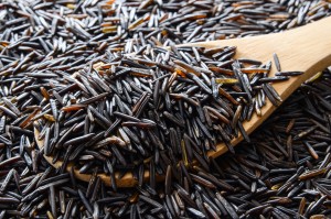 A pile of wild rice and a wooden spoon.