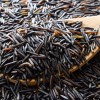 A pile of wild rice and a wooden spoon.