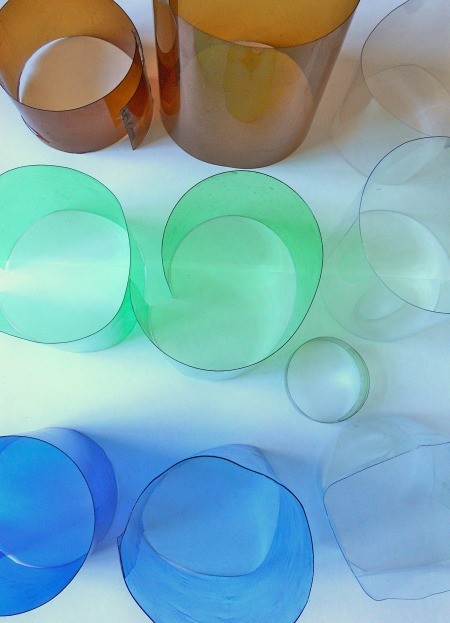 A collection of different colored cut soda bottles.