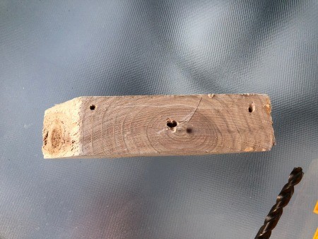 An angled piece of wood with a hole drilled in the middle.