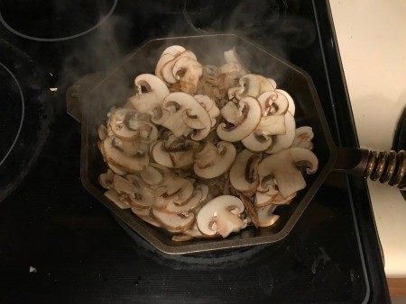 Grilling mushrooms and onions in a frying pan.