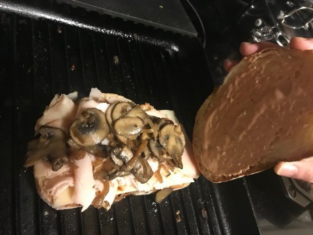 Placing the second slice of bread on the sandwich.