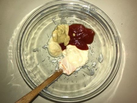 A mixing bowl with ketchup, mayo, mustard and horseradish.
