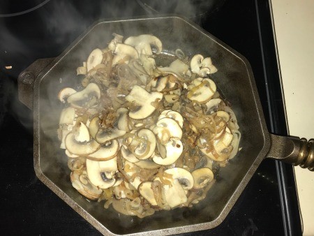 A frying pan with grilled mushrooms and onions.