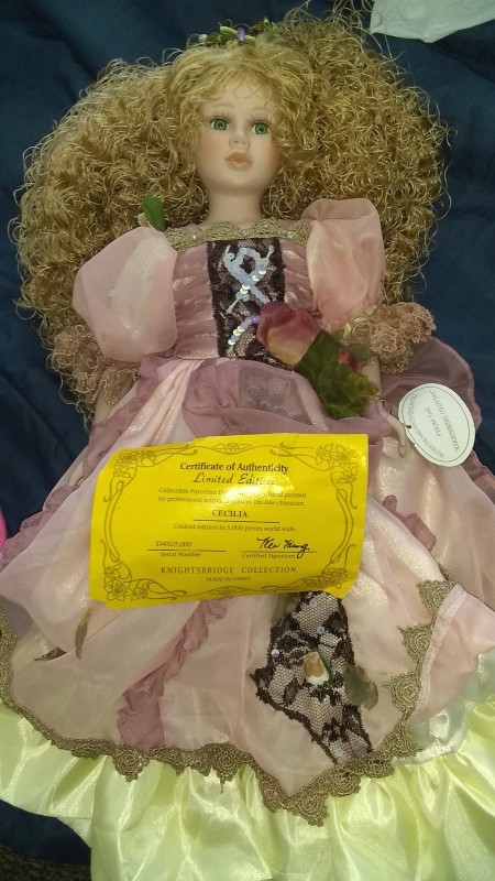 A decorative porcelain doll in a fancy pink dress.