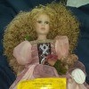 A decorative porcelain doll in a fancy pink dress.