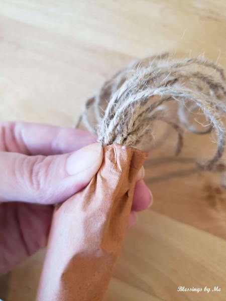 Adding twine to the top of a paper carrot.