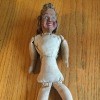 An old doll with no clothing.