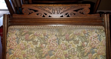 The carved top of a wooden chair.