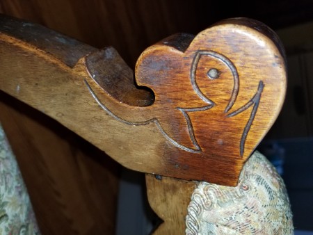 The carved arm of a wooden chair.