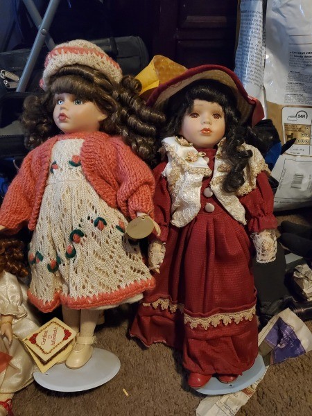 Two porcelain dolls with dark hair.