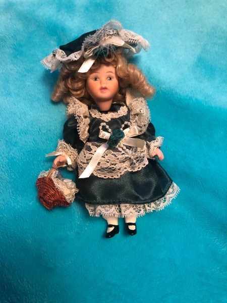 A small porcelain doll in a green and white dress.