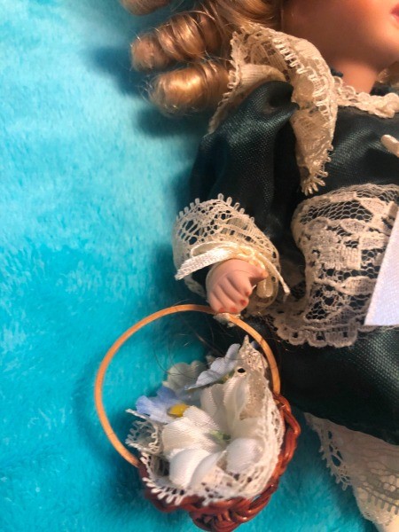 A porcelain doll holding a basket.