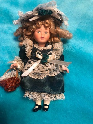 A small porcelain doll in a green and white dress.