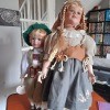 Two porcelain dolls in old fashioned outfits.