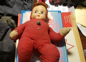 Baby doll with stuffed body in a red outfit.