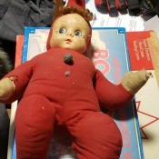 Baby doll with stuffed body in a red outfit.