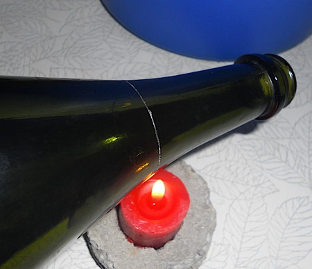Candle flame heating a scored glass bottle.