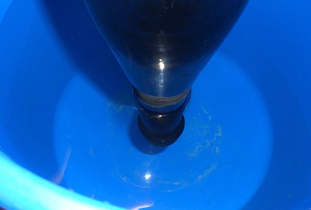 Glass bottle being dipped into a tub of water.