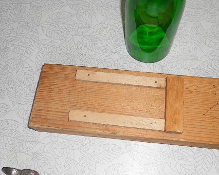 Wooden frame to hold glass bottle for cutting.