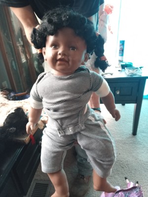 A porcelain toddler doll wearing a grey onesie.